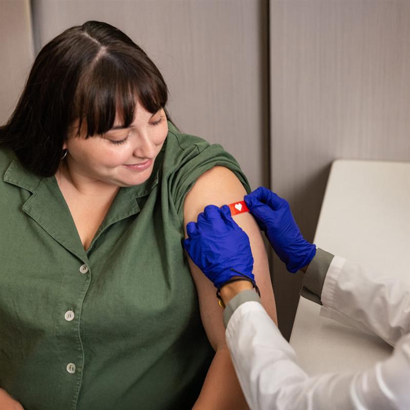 A CVS provider helps a patient get a vaccine required by U.S. Citizenship and Immigration Services.