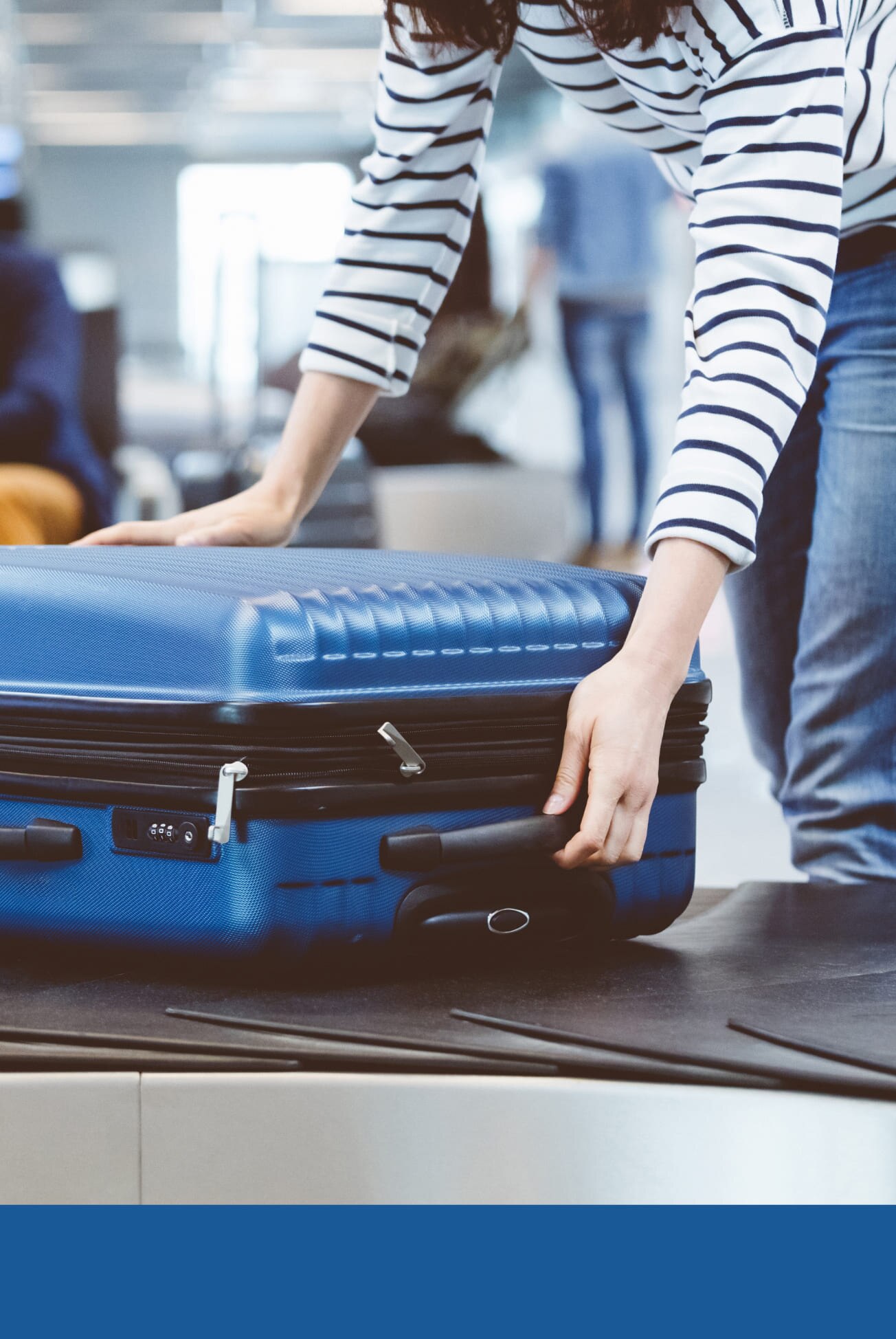 A woman closes her travel luggage at an airport.