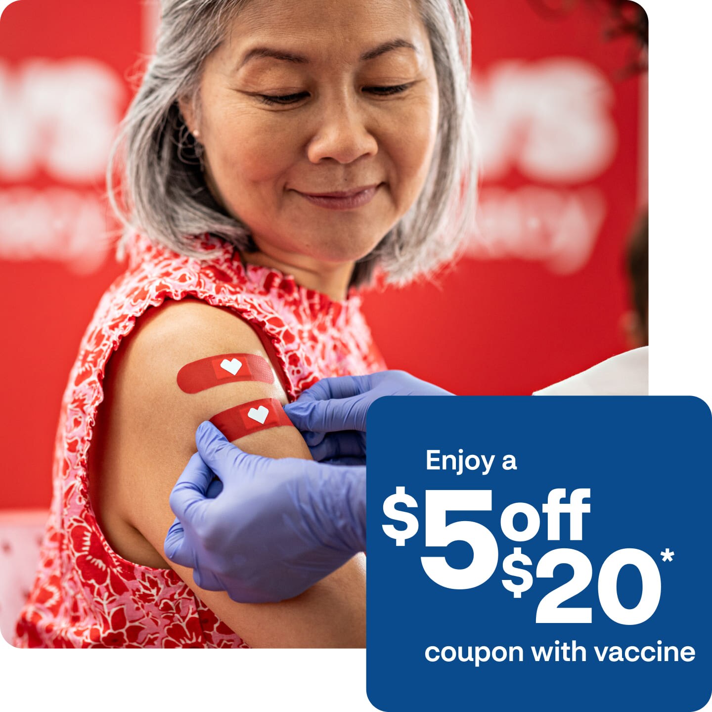 After getting multiple vaccines at the same time, an older patient looks down and smiles as a provider places two bandages on their arm.