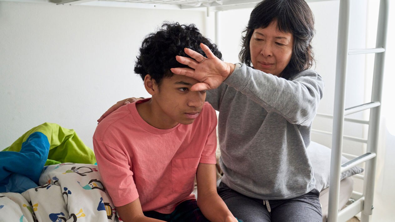 A mother checks her child’s forehead for signs of a fever.