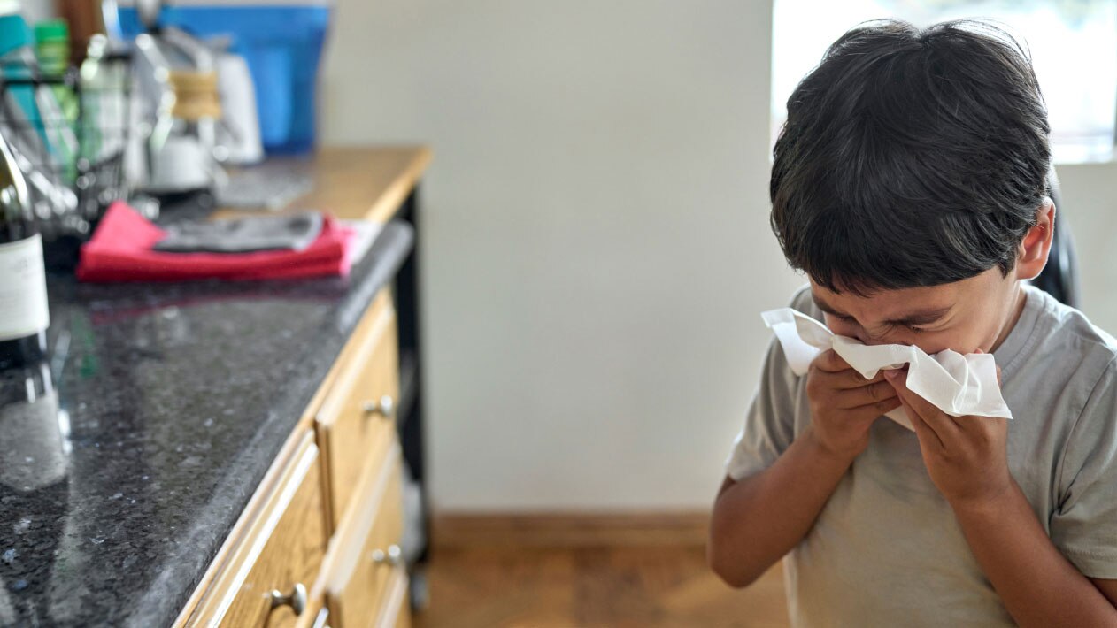 A child sneezes into a tissue.