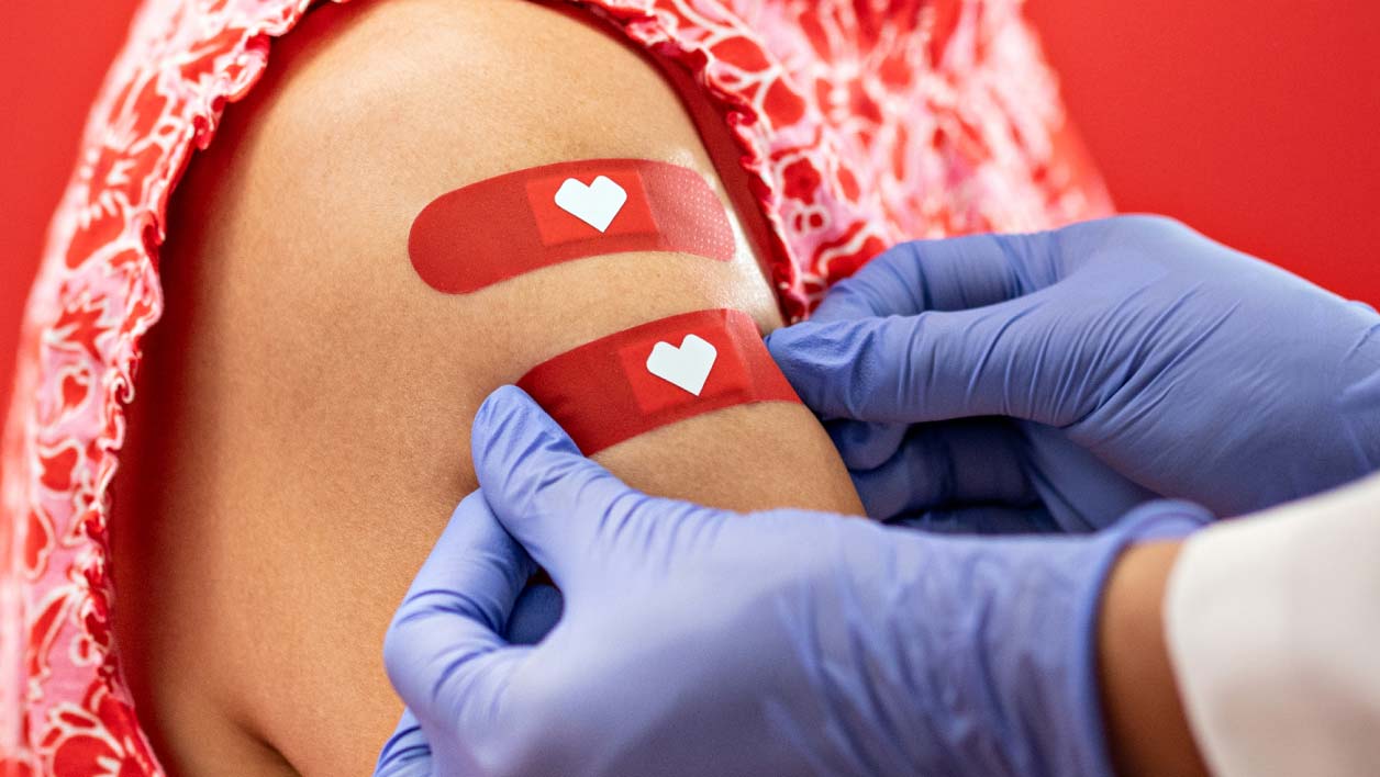 A patient getting multiple vaccinations at the same time has two bandages placed on their arm.