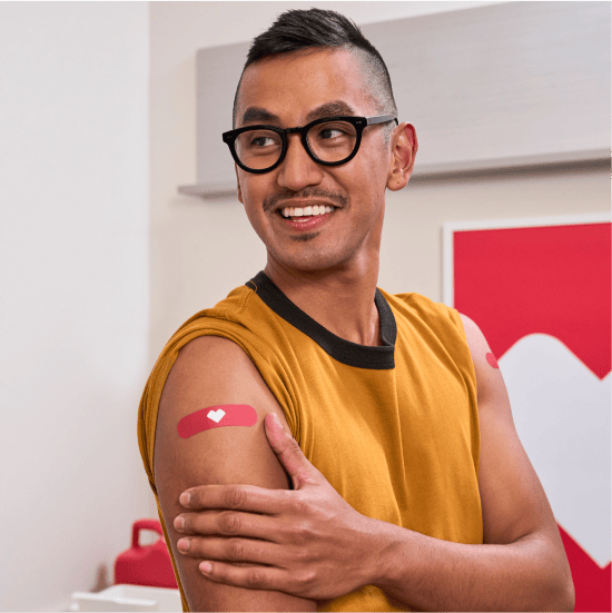 A person places a hand on their arm to show where they got vaccinated.