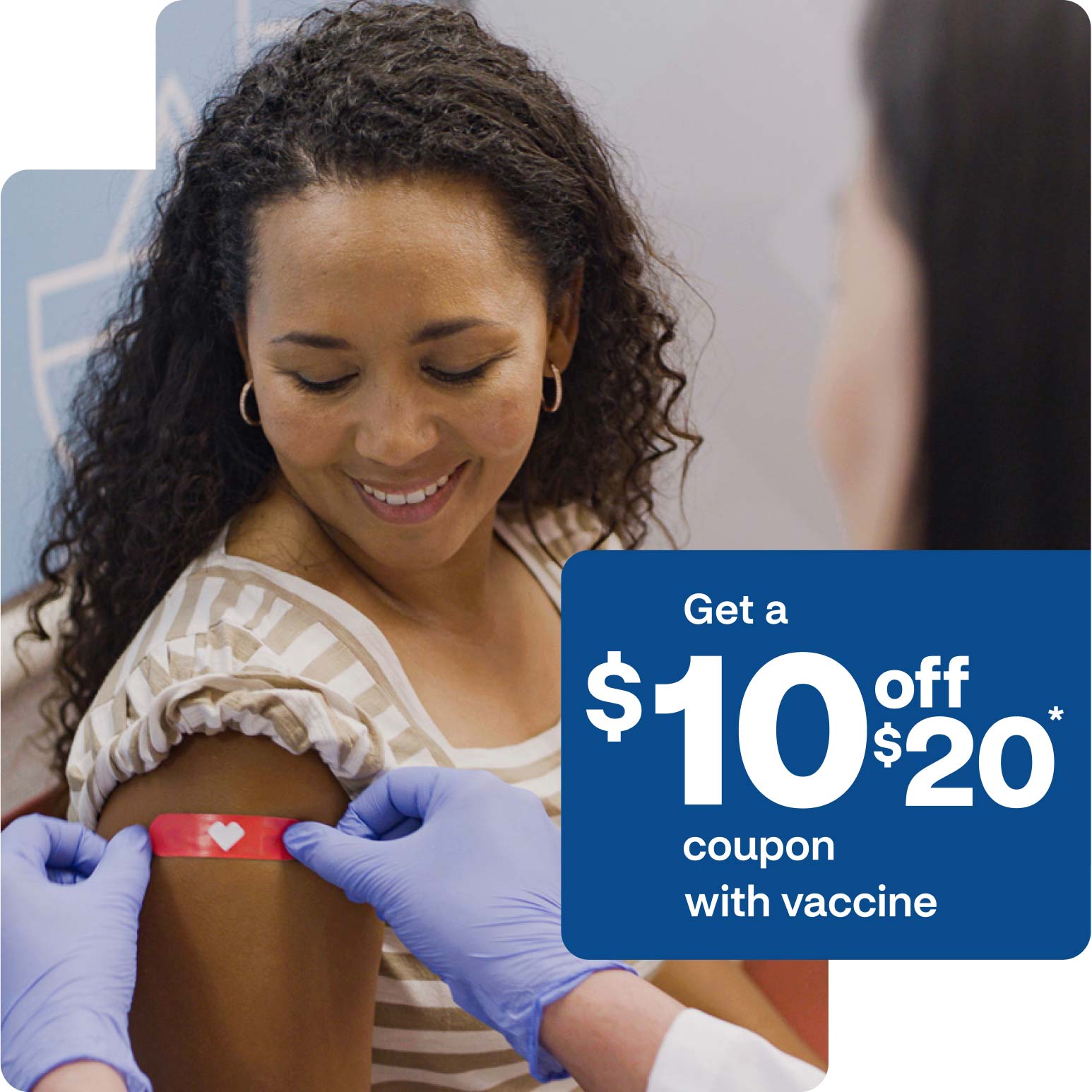 A flu shot patient smiles as a provider places a heart bandage on their arm.