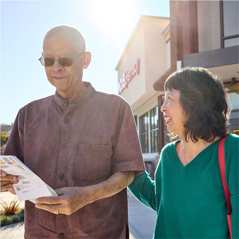 Two CVS customers smile as they leave a CVS Pharmacy location.